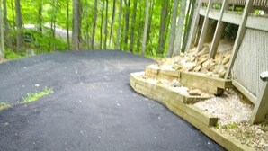 A paved outdoor area with a wooden deck and a stone wall.