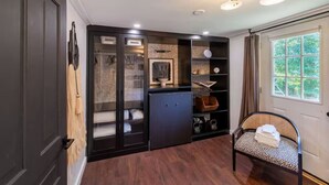 Um interior moderno com piso de madeira escura, um móvel de armazenamento com frente de vidro, um armário preto e uma cadeira de vime.