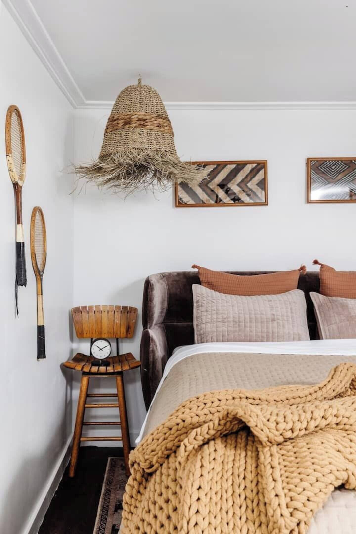 A bedroom with a bed, a hanging basket, a clock, and wall-mounted items.