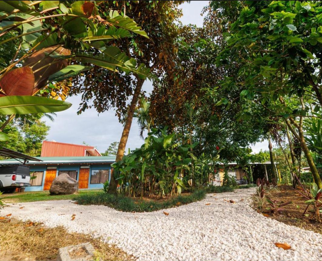 A hotel with a gravel pathway leading to a building with a red roof.