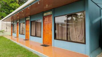 Un hotel con un área exterior cubierta, puertas de madera y fachada azul.