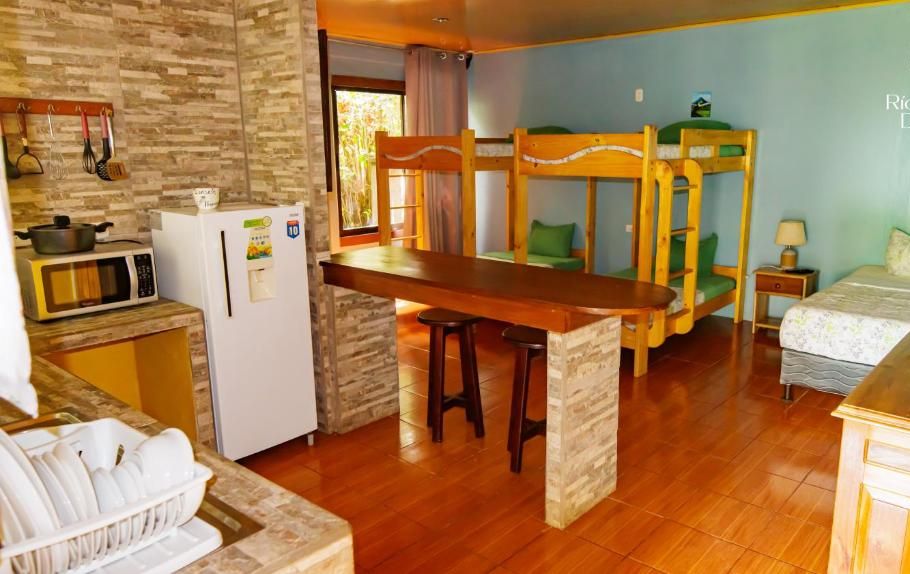 Una habitación de hotel compacta con literas, kitchenette y zona de comedor.