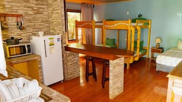 Una habitación de hotel compacta con literas, kitchenette y zona de comedor.