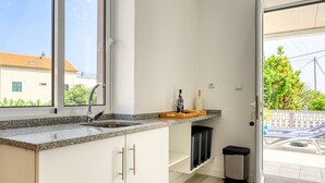 A kitchen with granite countertops, a sink, and a window overlooking a balcony. - Aunt Celeste's House I, a Home in Madeira (Ponta do Sol)