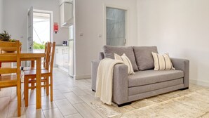 A modern living room with a grey sofa, wooden dining table, and chairs. - Aunt Celeste's House I, a Home in Madeira (Ponta do Sol)