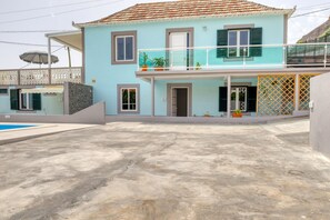 Ein zweistöckiges Haus mit Balkon, Pool und Garten.