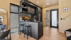Una cocina moderna con una isla central, taburetes de bar y un lavamanos empotrado.