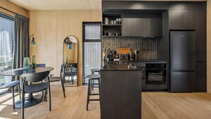 Cocina moderna con muebles oscuros, una isla central y un área de comedor con una mesa redonda y sillas.
