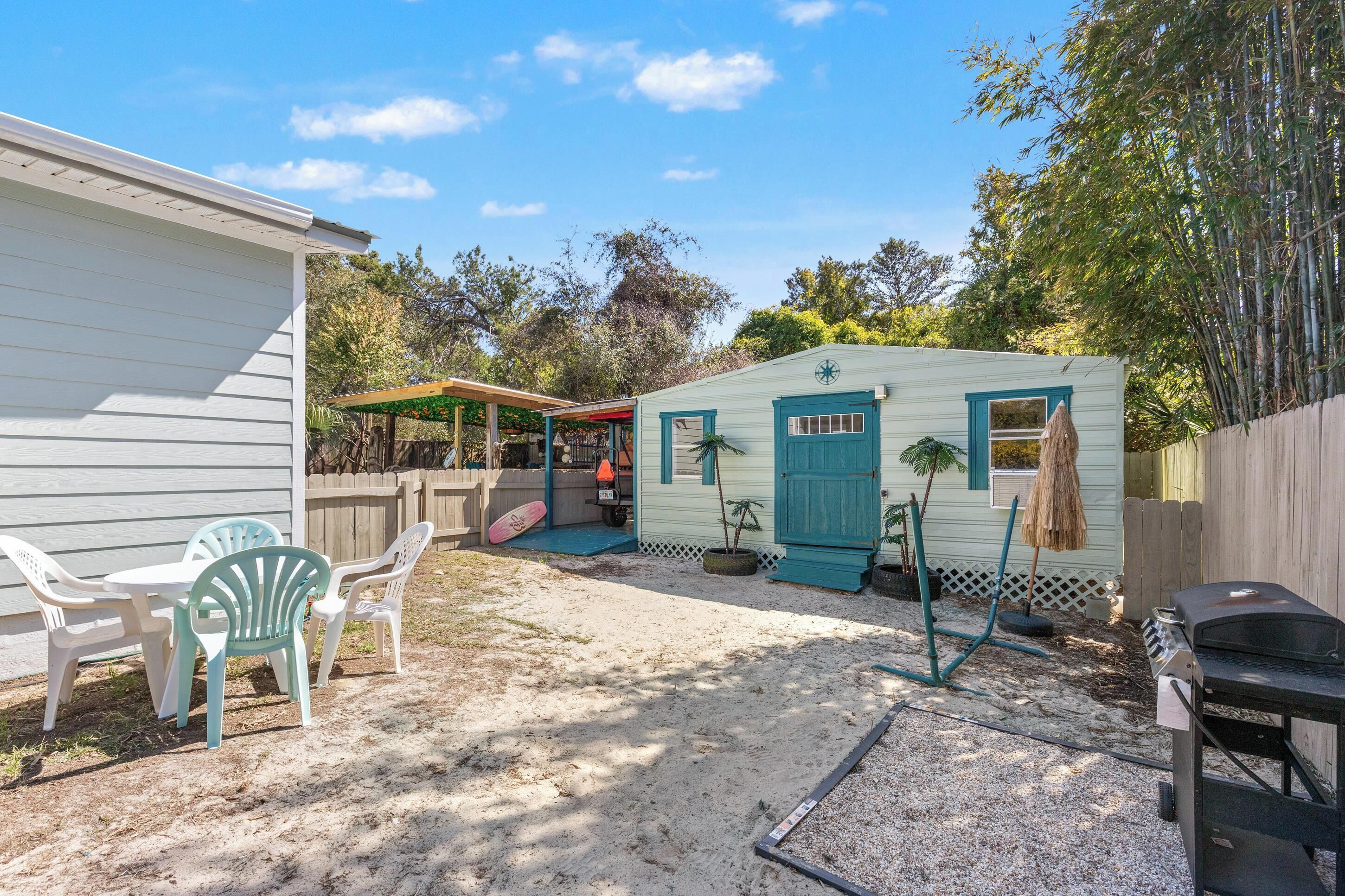 A backyard with a small shed, a grill, and a covered patio area.