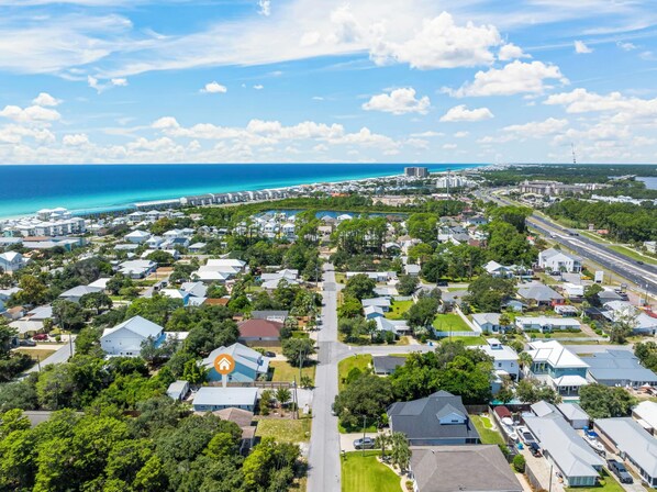 An aerial view of a coastal residential area with houses, roads, and a beach.