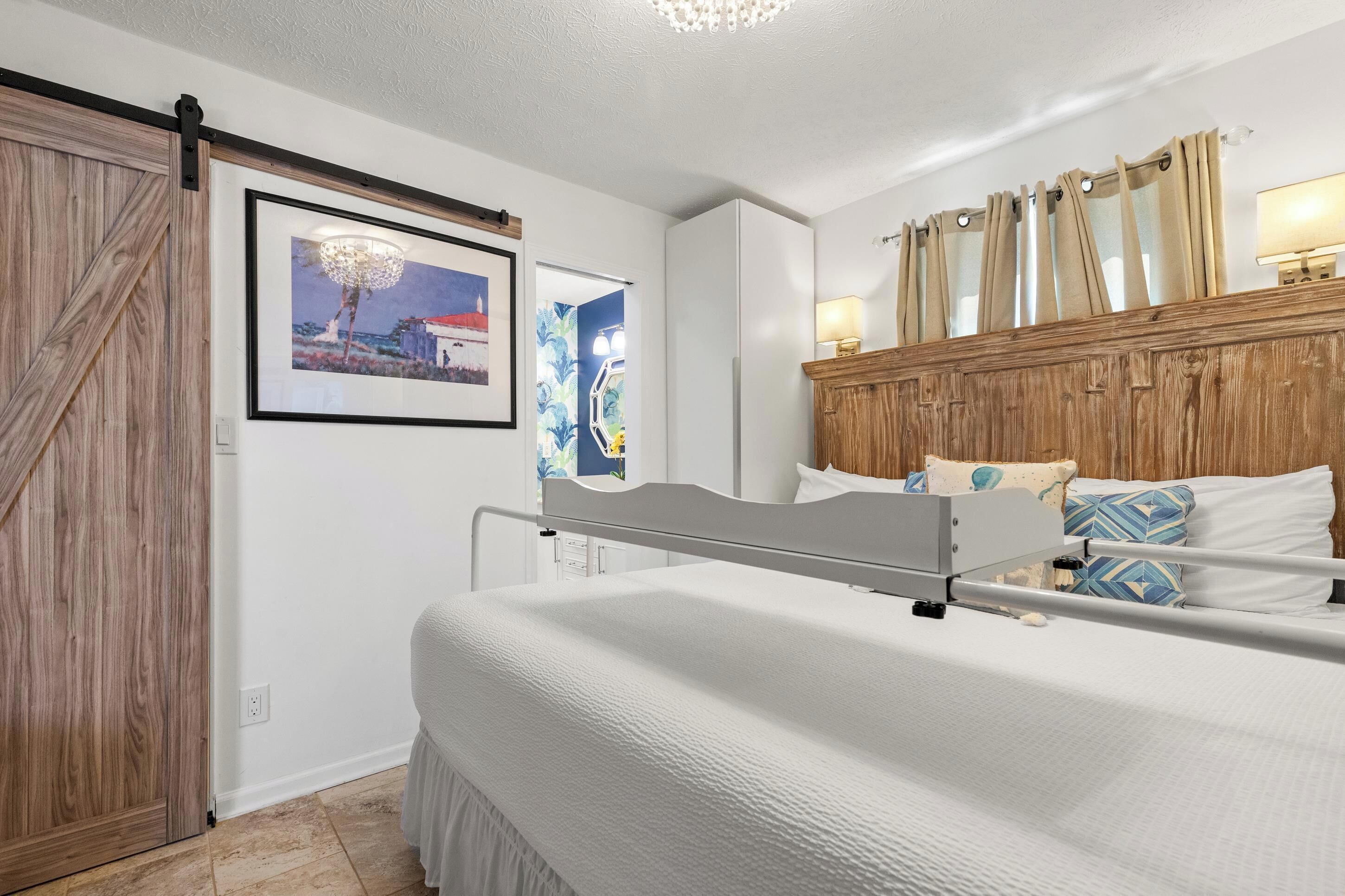 Une chambre à coucher avec un lit, une tête de lit en bois, un tableau accroché au mur et une porte coulissante de style rustique.