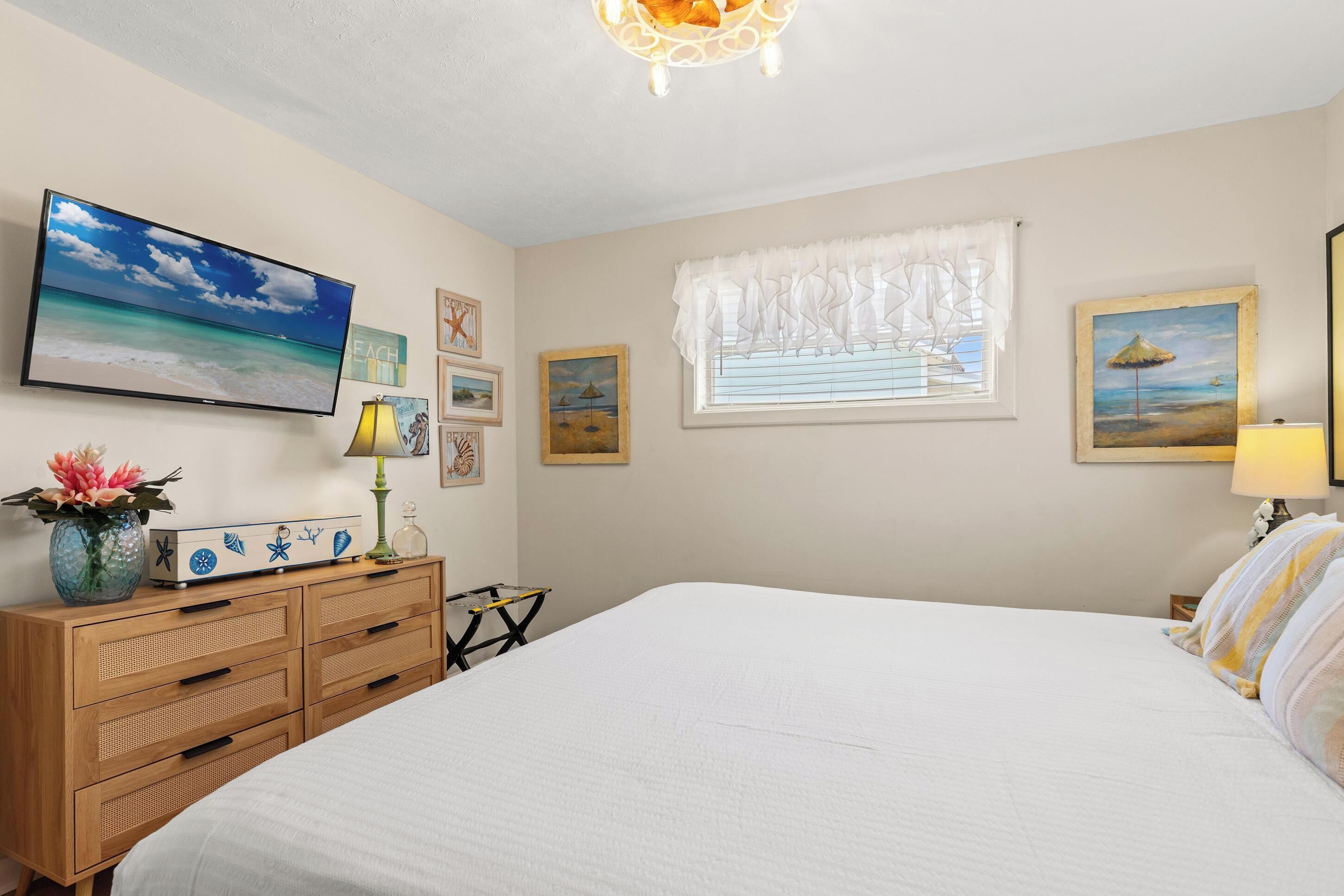 Un dormitorio con cama, cómoda, televisor y decoración en la pared.
