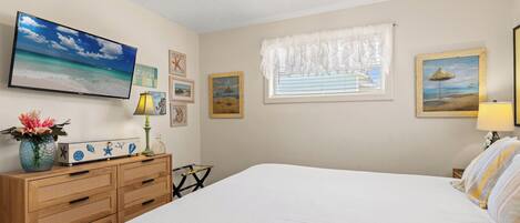 Un dormitorio con cama, cómoda, televisor y decoración en la pared.