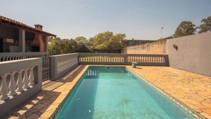Una piscina rectangular con solárium empedrado, rodeada por un muro bajo y una barandilla decorativa.