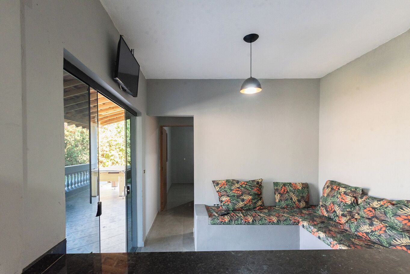 Un salon moderne avec un canapé, un téléviseur fixé au mur et un luminaire au plafond.
