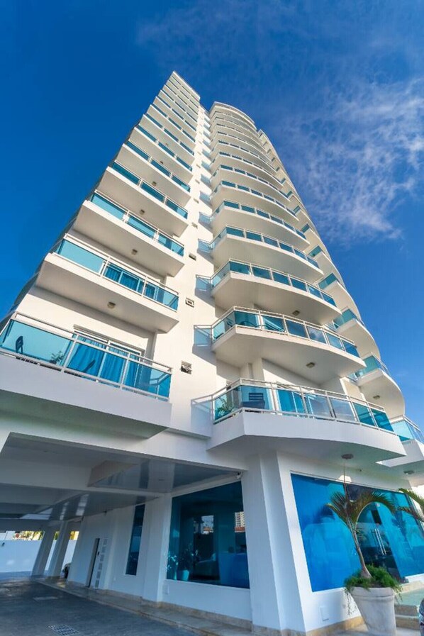 A tall, modern hotel with multiple balconies and large windows.