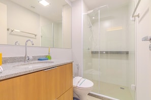 Ein modernes Badezimmer mit Granitplatte, einem Holz-Waschtisch, einer Duschkabine aus Glas und einer weißen Toilette.