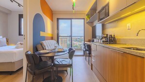 A modern hotel room with a dining area, a bed, and a kitchen. - Nex One Nhambiquaras (São Paulo)