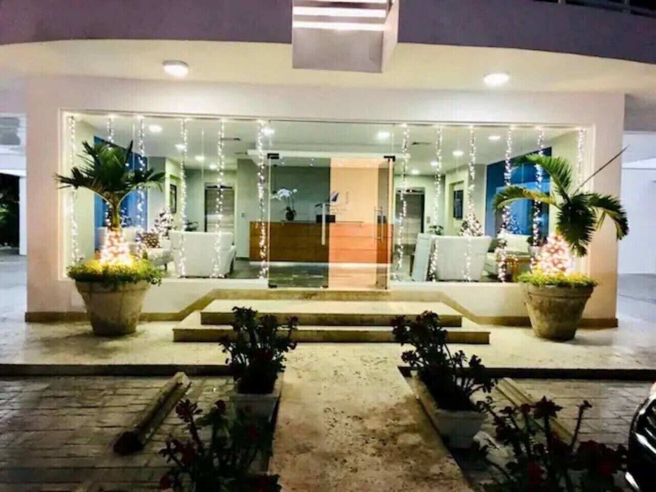 L'ingresso di un hotel con facciata in vetro, gradini che conducono alla porta e piante in vaso su entrambi i lati.