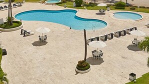 Un complexe hôtelier doté d’une grande piscine, de palmiers et offrant une vue sur l’océan.
