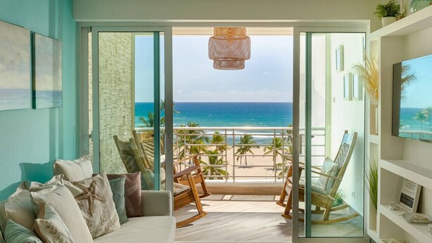 Un salon doté d’une grande porte vitrée donnant sur un balcon avec vue sur l’océan.