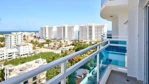 A high-rise building with a balcony overlooking a residential area and a clear view of the ocean.