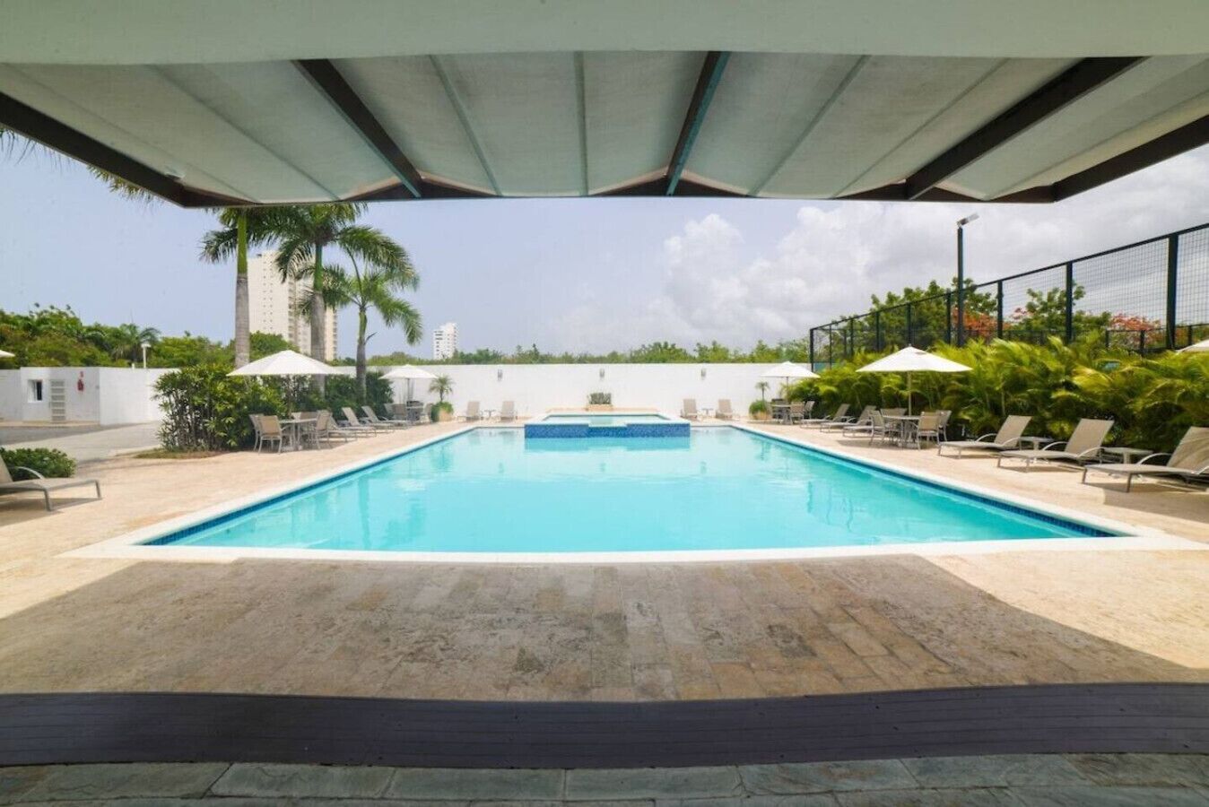 Vista de la piscina desde el área social, con sillas a la orilla para que puedas descansar