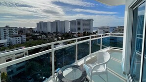 Ein Balkon mit Glasgeländer und Blick auf eine Skyline mit mehreren Hochhäusern und einem klaren Himmel.