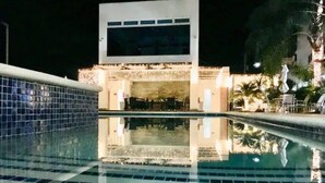 Ein Schwimmbecken mit Fliesenboden und einem Gebäude im Hintergrund.