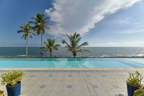 A swimming pool with a view of the ocean and palm trees.