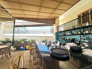 An indoor bar area with a pool table, bar stools, and a variety of bottles and glasses on shelves.