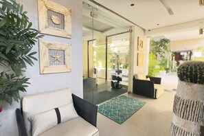 A modern interior with a sofa, a patterned rug, and a cactus plant.