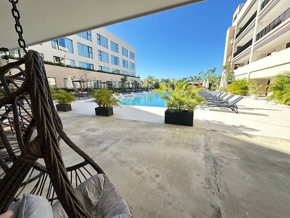 A poolside area with lounge chairs, a concrete floor, and a building in the background.