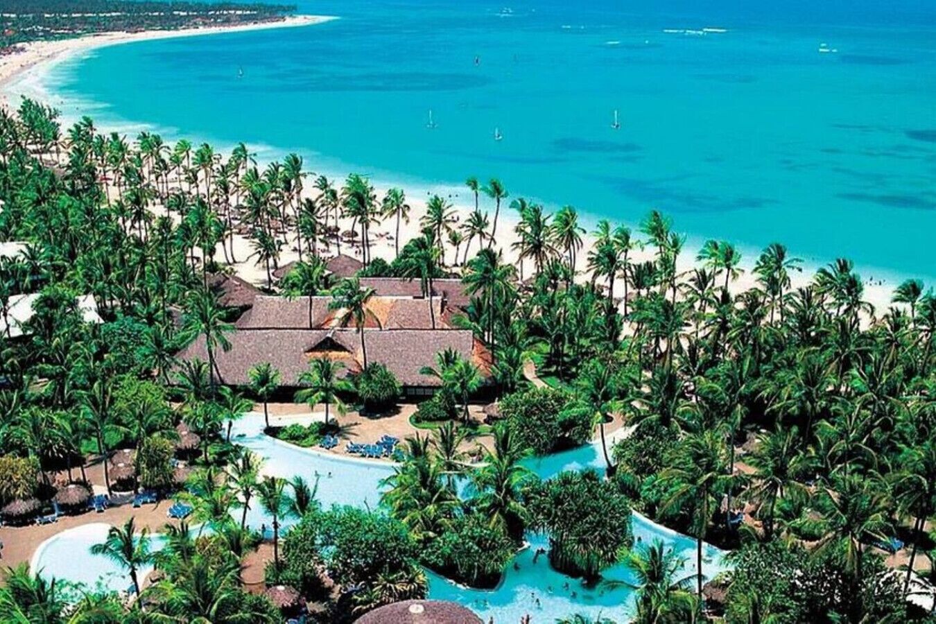 A resort with a pool, palm trees, and a beach.