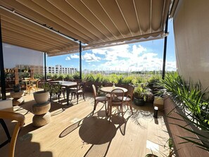 Eine Außenpatio-Terrasse mit Holzmöbeln, Topfpflanzen und Blick auf die Stadtlandschaft.
