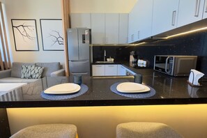 Eine moderne Küche mit schwarzem Arbeitsplatz, zwei weißen Tellern, einem Kühlschrank und einer Mikrowelle.