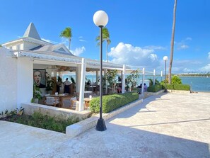 A seaside restaurant with outdoor seating, a covered area, and a view of the ocean.