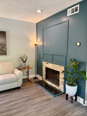 Un salon avec une cheminée, un canapé, une lampe et une plante en pot.