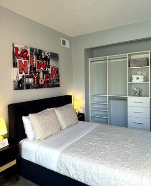 A neatly made bed with a headboard, a bedside lamp, and a wall art piece. - Stylish Midtown Atlanta Studio •Walk to Piedmont Park+ Free Covered Parking (Atlanta)