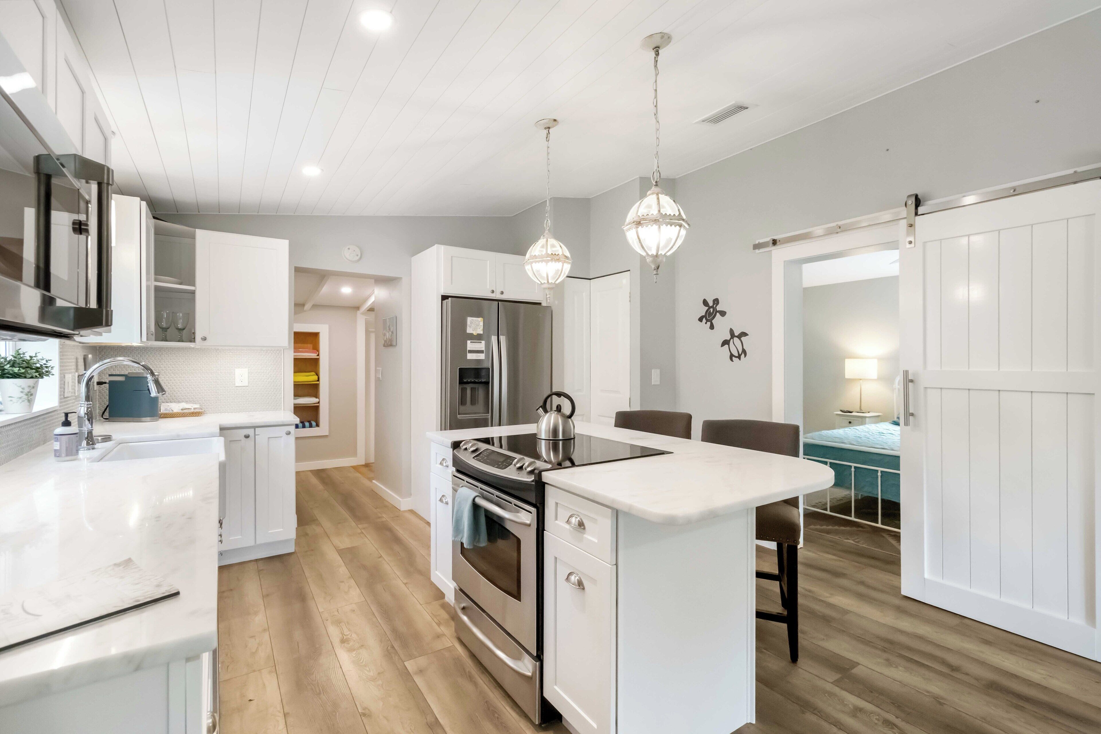 A modern kitchen with white cabinetry, stainless steel appliances, and a central island.