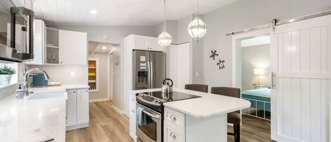 A modern kitchen with white cabinetry, stainless steel appliances, and a central island.
