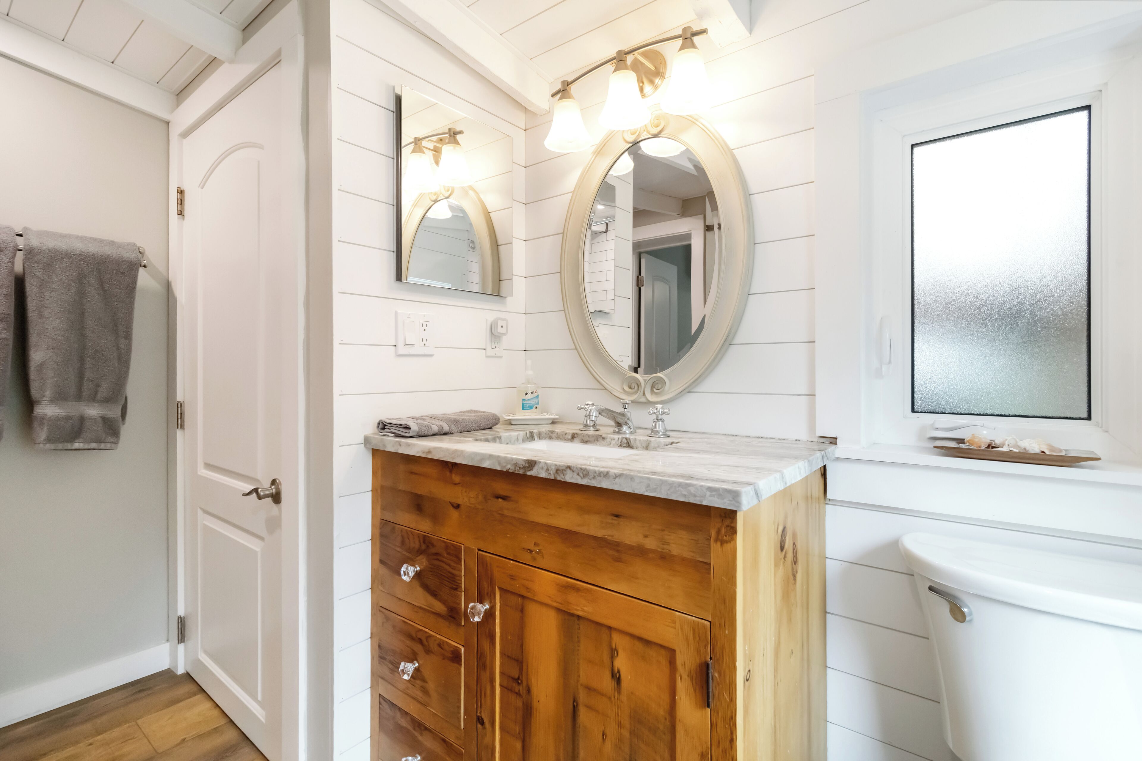 Un bagno con un mobile vanitario in legno, un water bianco e un ampio specchio illuminato.