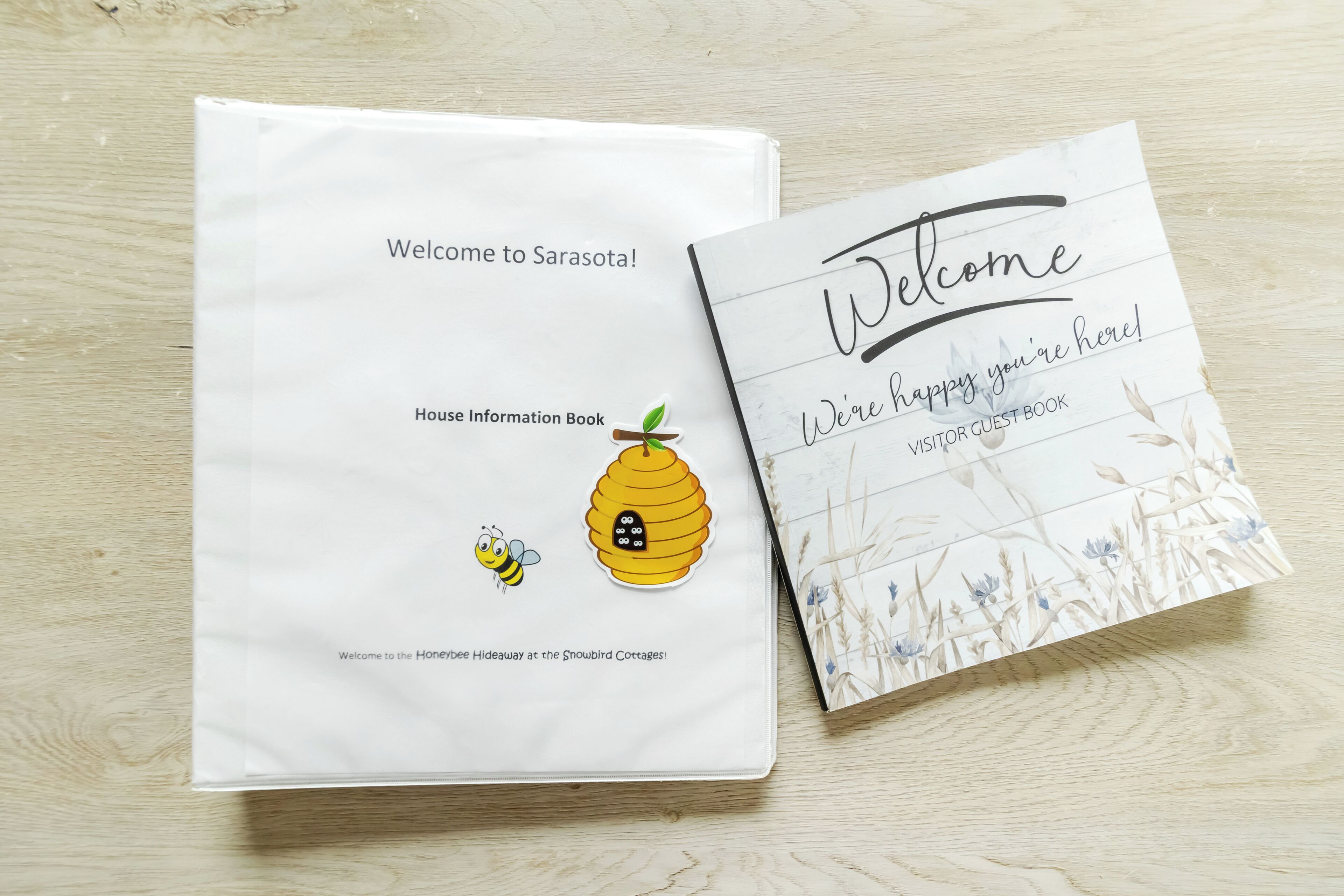 Un cartello di benvenuto bianco e un libro degli ospiti con un’illustrazione di un’ape.