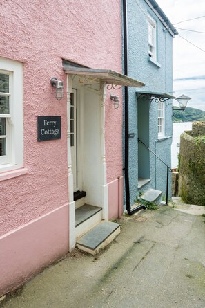A pink and blue cottage with a sign reading "Ferry Cottage."