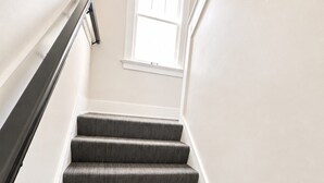 A staircase with a handrail, carpeted steps, and a window at the top. - Franklin Haus - Frankenmuth Vacation Homes (Frankenmuth)