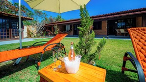 A patio with outdoor seating, a table with a bottle of champagne, and a large umbrella. - Brisas do Oceano Lofts (Buzios)