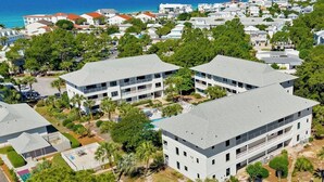 A multi-story hotel with a pool, surrounded by greenery and a view of the ocean. - Fully renovated! Great rates on a charming 2/2 steps from the beach! (Santa Rosa Beach)