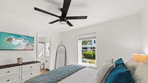 A bedroom with a bed, a ceiling fan, a window with blinds, a painting on the wall, and a dresser. - Fully renovated! Great rates on a charming 2/2 steps from the beach! (Santa Rosa Beach)