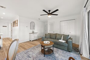 A living room with a ceiling fan, a sofa, a coffee table, and a dining area with a chair. - Fully renovated! Great rates on a charming 2/2 steps from the beach! (Santa Rosa Beach)