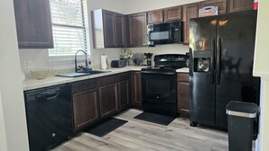 Una cocina moderna con gabinetes de madera oscura, un refrigerador de acero inoxidable, un microondas y un lavavajillas.